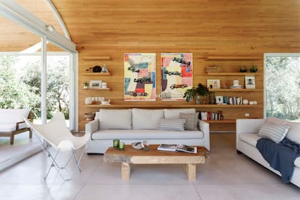 Sillones (Tapicería Do Braz) con almohadones de Lote Propio, silla ‘BKF’ (Morph) y mesa baja de ciprés (Carpintería Sebastián Fernández Lando) con velas (Bohemia Velas), cuenco de papel maché (Mamá Elefanta) y obra de arte textil (Entrelazados). Como contrapunto con el revestimiento de madera, coloridas obras en fieltro (Virginia Caorsi Resúa).