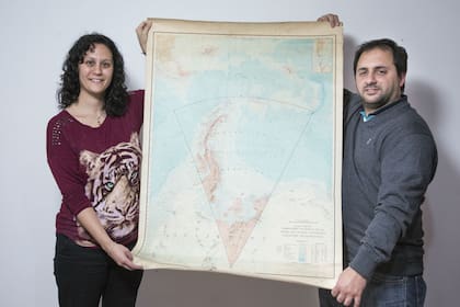Silvina y Rubén sostienen un mapa de la Antártida Argentina