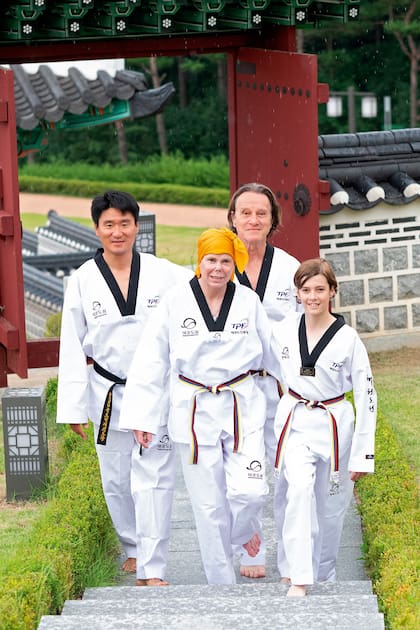 Simeon con sus padres y un instructor, en 2024, tras ganar el cinturón verde de taekwondo en Corea. La familia, que comparte la pasión por la aventura, está planeando una travesía transoceánica en una balsa de juncos para este año