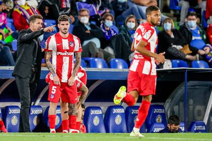 Simeone le da indicaciones a De Paul antes de ingresar durante un partido de Atlético de Madrid, mientras Renan Lodi pasa cerca...