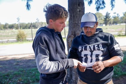 Simón Pioltino mira su lista de caballos con un colaborador; el jugador de 22 años viste sobre el césped la camiseta del glorioso Venado Tuerto.
