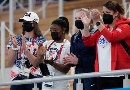 Simone Biles de los Estados Unidos, segunda a la izquierda, y sus compañeros de equipo aplauden cuando Sunisa Lee recibe la medalla de bronce por las barras asimétricas, durante la final de aparatos femeninos de gimnasia artística.