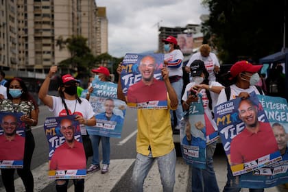 Simpatizantes de los candidatos del partido gobernante sostienen carteles de Héctor Rodríguez y el candidato a la alcaldía de Sucre, José Vicente Rangel, durante un mitin de clausura de campaña en Caracas, Venezuela