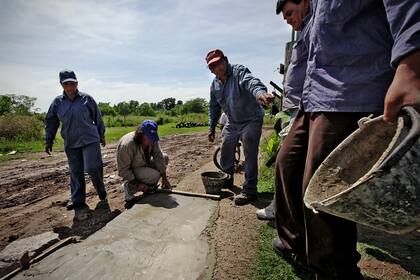 Sin ayuda. La cooperativa de Eva Aquino construye la vereda de la calle Valle Armonía, lo único que se mantiene firme cuando llueve en González Catán. El Ministerio no aporta ni el cemento.