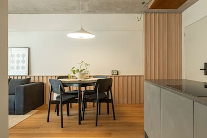Sin gastar de más, Guerberoff resolvió el revestimiento del living-comedor con un tablero varillado en melamina: “Era la primera vez que usaba ese material y quedé muy contenta con el resultado”. Mesa con sillas de madera (Estudio Te).