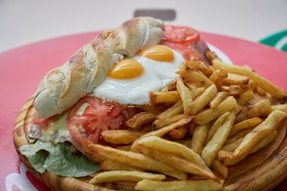 Sin palabras: la milanesa está debajo del huevo en una de las versiones de este sándwich que sale siempre para compartir. Todos se sirven con papas.