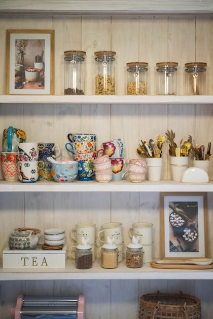 Sin puertas, los estantes lucen sus frascos, tazas y elementos de cocina