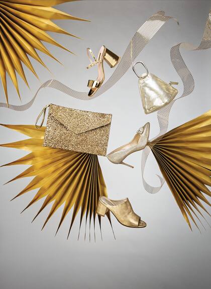 Sobre de glitter dorado (Las Pepas). Sandalias metalizadas (Las Pepas). Clutch triangular de cuero (Uma). Stiletto con piedras en capellada (Blaquè). Zueco de cuero con taco forrado (A Pie).