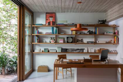 Sobre el escritorio (Boulevard), edificios y monumentos históricos de Buenos Aires en madera (Lola y Chango). Sillas (Nórdico). Lámpara colgante (Perfecta Iluminación). Biblioteca diseñada por Monoestudio, en petiribí encerado sin lustre.
