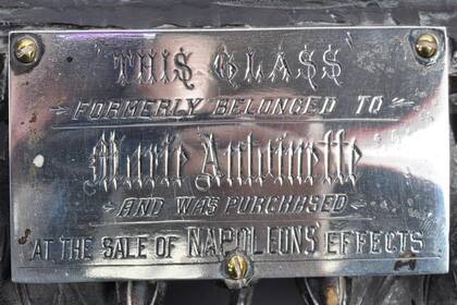 Sobre el marco hay una placa de vidrio que dice que el espejo perteneci a Mara Antonieta y que "fue adquirido en una venta de objetos de Napolen"