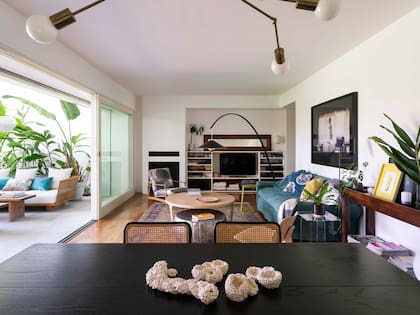 Sobre el sofá retapizado en lino verde, fotografía enmarcada (Lorena Guillén Vaschetti). Almohadones (Pezkoi). Mesa de centro en pergamino (Harturo). Mesas auxiliares en acrílico transparente (Ries) y metal laqueado (Habito). Lámpara de pie (Federico Churba).