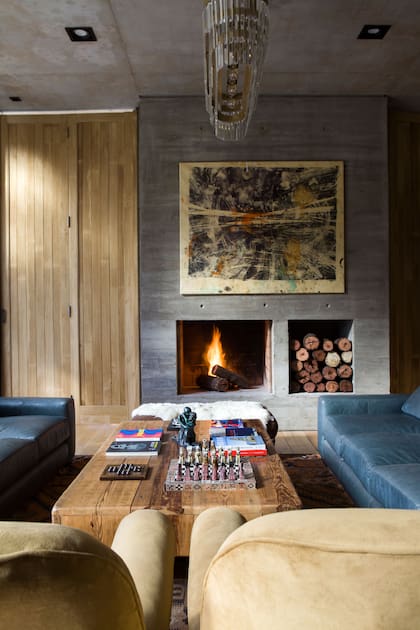 Sobre la chimenea diseñada por al arquitecta Inés Fuseo, obra de Eduardo Hoffmann. Iluminación colgante (Vantier Home & Deco). Mesa ratona (Poltrona Home). Sofás de cuero azules (By Ignacio Ortiz).