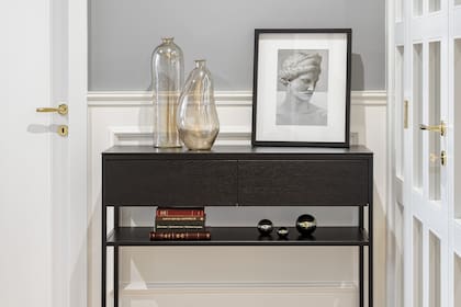 Sobre la consola de hierro y roble (Paulo Valcic) objetos de vidrio, libros y una foto del artista español Naro Pinosa.