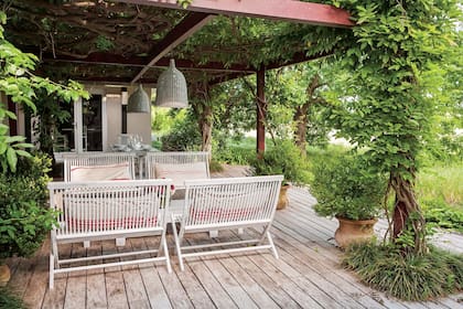 Pérgola con una envidiable glicina que protege el juego de mesa y sillas plegables que María le compró usado a una colega hace tres décadas.