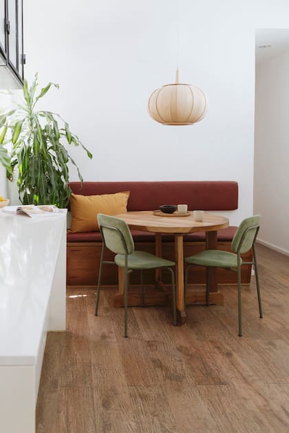 Sobre la izquierda, se ve la mesada de la cocina. Banco y mesa extensible en petiribí (Cántaro-Bardó). Sillas tapizadas (Estudio Te). Lámpara colgante ‘Mandarina’ (Dimm).