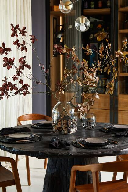 Sobre la mesa de madera quemada, vajilla negra de Dukaan Home.