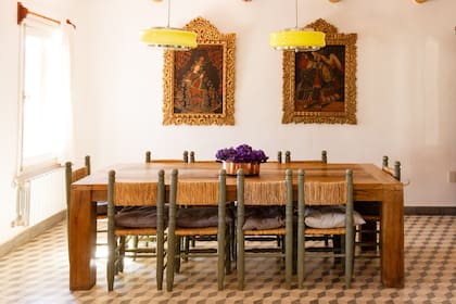 Sobre la mesa del comedor (Paul French Gallery), las tulipas vintage del Mercado de Pulgas de Dorrego contrastan con un par de pinturas cuzqueñas conseguidas en un remate