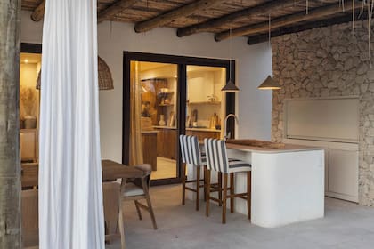 Sobre prácticos pisos de porcelanato 'Le Pietre del Casale' (ILVA), que imitan la piedra, una barra con terminaciones curvas. Las lámparas se buscaron en el mismo tono de la parrilla.