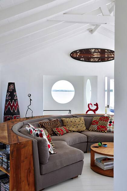 Sofá curvo, diseño del arquitecto Diego Montero, dueño de casa. Tambor uruguayo, esculturas de hierro (Lola Puig) y de aluminio roja (Jorge Blanco) y tabla de surf (Surf for Art).
