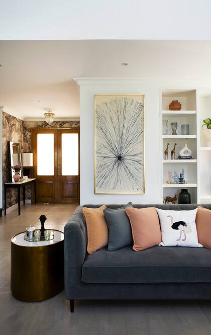 Sofá de terciopelo teñido a mano, almohadones lisos que combinan colores que se retoman en el bordado y taburete dorado (todo de Agustina Cerato).