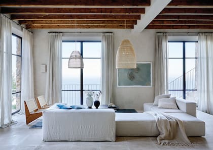 Sofá modular en lino, pantallas de fibras naturales y sillas de madera con respaldo de tiento de More Decor, el brazo de interiorismo del Estudo a cargo de la reforma. Cuadro de Guillem Nadal