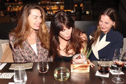 Solange Cubillo y Lucrecia Gamundi
rodean a la cumpleañera mientras sopla
las velitas