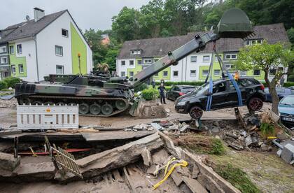 Soldados de la Bundeswehr recuperan un automóvil destruido con un vehículo blindado de ingenieros Dachs durante los trabajos de limpieza de los graves daños causados ​​por la tormenta en el distrito de Hohenlimburg. 