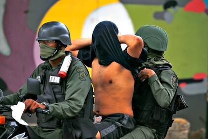 Soldados de la Guardia Nacional Bolivariana llevan un detenido