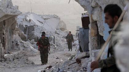 Soldados del ejército sirio caminan por las devastadas calles de Aleppo
