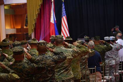 Soldados filipinos y estadounidenses saludan delante de sus banderas nacionales mientras suenan sus himnos nacionales durante la ceremonia de apertura del ejercicio militar conjunto "Balikatan" en el cuartel general militar de Quezon City, en los suburbios de Manila, el 11 de abril de 2023.