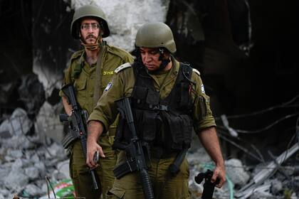 Soldados israelíes pasan junto a casas destruidas por milicianos de Hamas en el kibbutz Be'eri, Israel