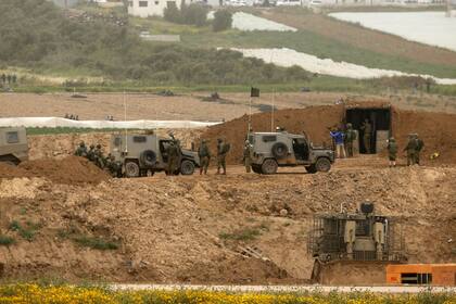 Soldados israelíes reunidos cerca de una barrera de tierra a lo largo de la valla fronteriza.