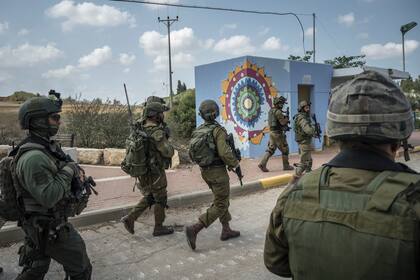 Soldados israelíes se reúnen frente a Kfar Azza, un pueblo al otro lado de la frontera de Gaza que fue atacado por pistoleros palestinos, en Israel, el martes 10 de octubre de 2023.