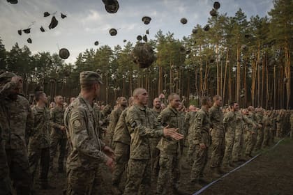 Soldados recién reclutados lanzan sus gorras mientras celebran el fin de su entrenamiento en una base militar cercana a Kiev, Ucrania, el lunes 25 de septiembre de 2023.