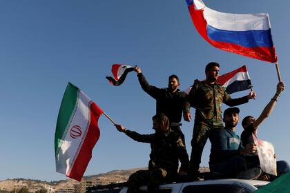 Soldados sirios agitan las banderas de Siria, Iran y Rusia durante una protesta contra los ataques aéreos de Estados Unidos