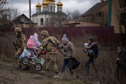 Soldados ucranianos ayudan a una familia a cruzar el río Irpin, en las afueras de Kiev, el 5 de marzo de 2022.