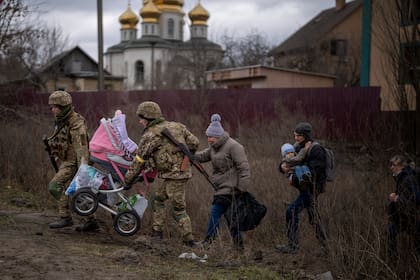 Soldados ucranianos ayudan a una familia que huye a cruzar el río Irpin en las afueras de Kiev, Ucrania, el sábado 5 de marzo de 2022.