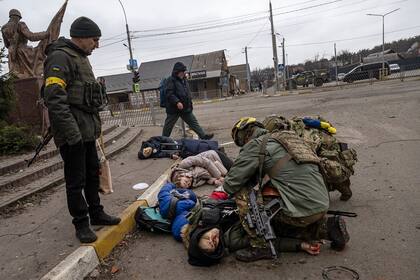 Soldados ucranianos intentan salvar al padre de una familia de cuatro, el único que todavía tenía pulso, luego de ser alcanzados por un proyectil de mortero mientras intentaban huir de Irpin, cerca de Kiev.