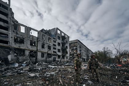 Soldados ucranianos pasan junto a casas arruinadas por los bombardeos rusos en Bakhmut, región de Donetsk, Ucrania,