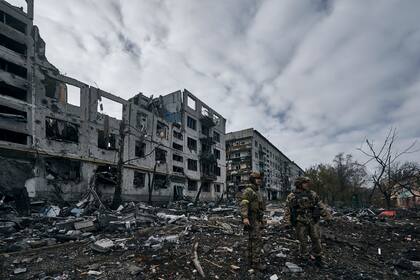 Soldados ucranianos pasan junto a casas arruinadas por los bombardeos rusos en Bakhmut, región de Donetsk, Ucrania, jueves 10 de noviembre de 2022. 