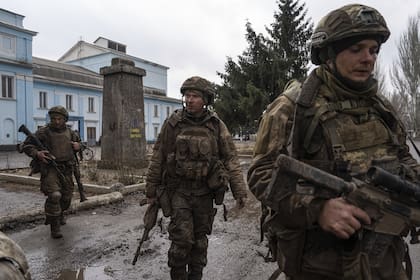Soldados ucranianos que recientemente regresaron de las trincheras de Bakhmut caminan por una calle en Chasiv Yar, Ucrania, el miércoles 8 de marzo de 2023. 