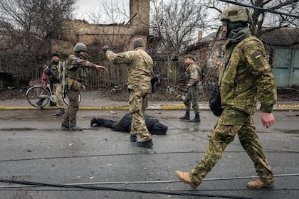 Soldados ucranianos recuperan el cadáver de un civil a un cable y revisan que no tenga trampas explosivas en el suburbio Bucha de Kiev, Ucrania