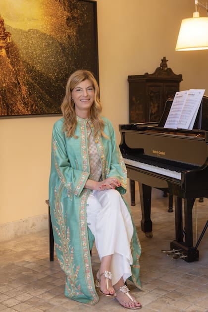 Soledad, con una impactante túnica de Rapsodia, en la entrada de la casa, donde hay
un piano instalado, que toca uno de sus hijos;
la inmensa obra que está detrás fue hecha
por ella: se trata de un trabajo realizado con
fotocollage