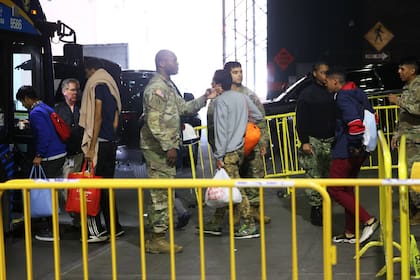 Solicitantes de asilo abordan un autobús de camino a un refugio en la terminal de autobuses de la Autoridad Portuaria, el 18 de mayo de 2023, en la ciudad de Nueva York