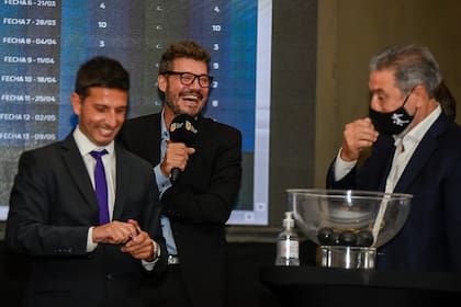 Marcelo Tinelli, presidente de la Liga Profesional, ríe. A su lado, Pascual Caiella (vicepresidente de Estudiantes de La Plata) se acomoda el barbijo luego de sacar una de las bolillas.