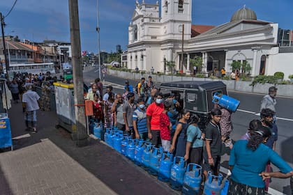 La gente espera en una fila con garrafas vacías para comprar gas doméstico en un centro de distribución en Colombo, Sri Lanka, el martes 12 de julio de 2022