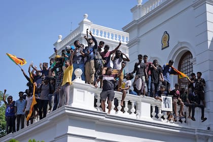 Manifestantes de Sri Lanka, algunos con banderas nacionales, tras asaltar la oficina del primer ministro Ranil Wickremesinghe, exigiendo su dimisión después de que el presidente Gotabaya Rajapaksa huyera del país en medio de la crisis económica en Colombo, Sri Lanka, miércoles 13 de julio de 2022. 