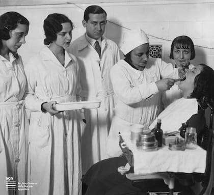 Srtas. Iride Perrotti, Blanca Enz, Aida Chiappe y Aida Bragagnolo, alumnas de 4to. año de Odontología, efectuando una extracción, dirigidas por el Dr. Piaggio. Facultad de Medicina, 1932.