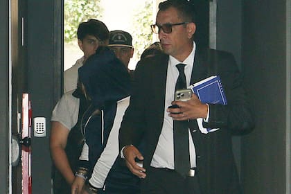 Su abogado, presente en el traslado. Detrás de él se la ve a Morena con un buzo azul y blanco con capucha y esposada