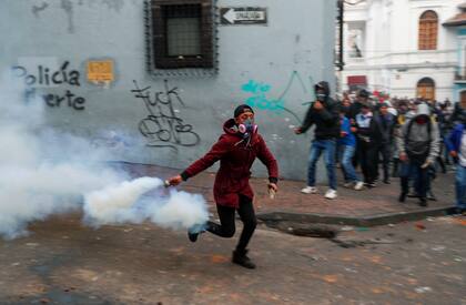 Un manifestante arroja un cartucho de gas lacrimógeno durante una protesta contra las medidas de austeridad del presidente de Ecuador, Lenin Moreno